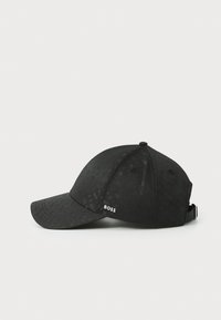 Svart baseballcap med strukturert stoff, buet brem og justerbar stropp. Har en diskret hvit "BOSS"-logo på siden.