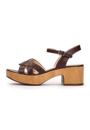 Brązowy skórzany sandał z drewnianym obcasem na platformie, krzyżującymi się paskami na palcach oraz paskiem wokół kostki z zapięciem na sprzączkę.