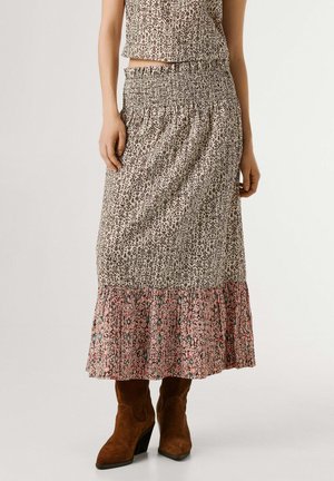 Donna che indossa una gonna midi a vita alta con fantasia, orlo arricciato e stivaletti alla caviglia in camoscio marrone.