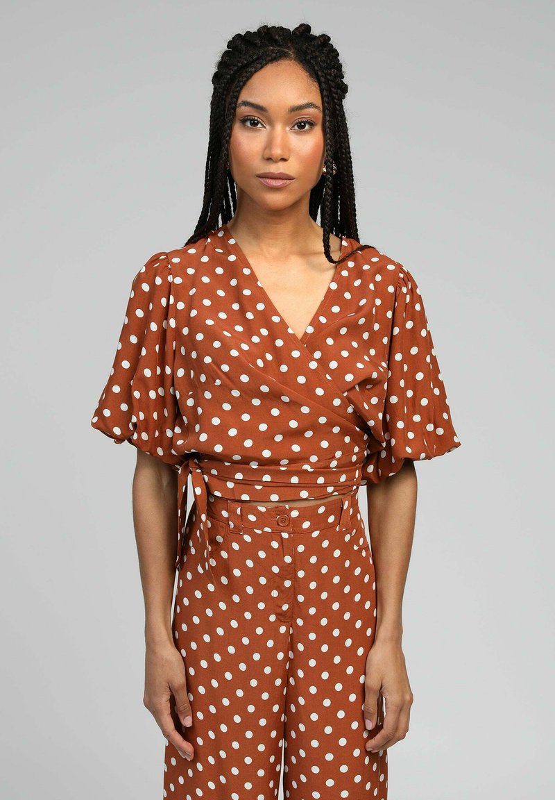 Haut croisé à pois marron avec des manches ballons courtes et un pantalon taille haute assorti, présentant un décolleté en V et un détail à nouer à la taille.