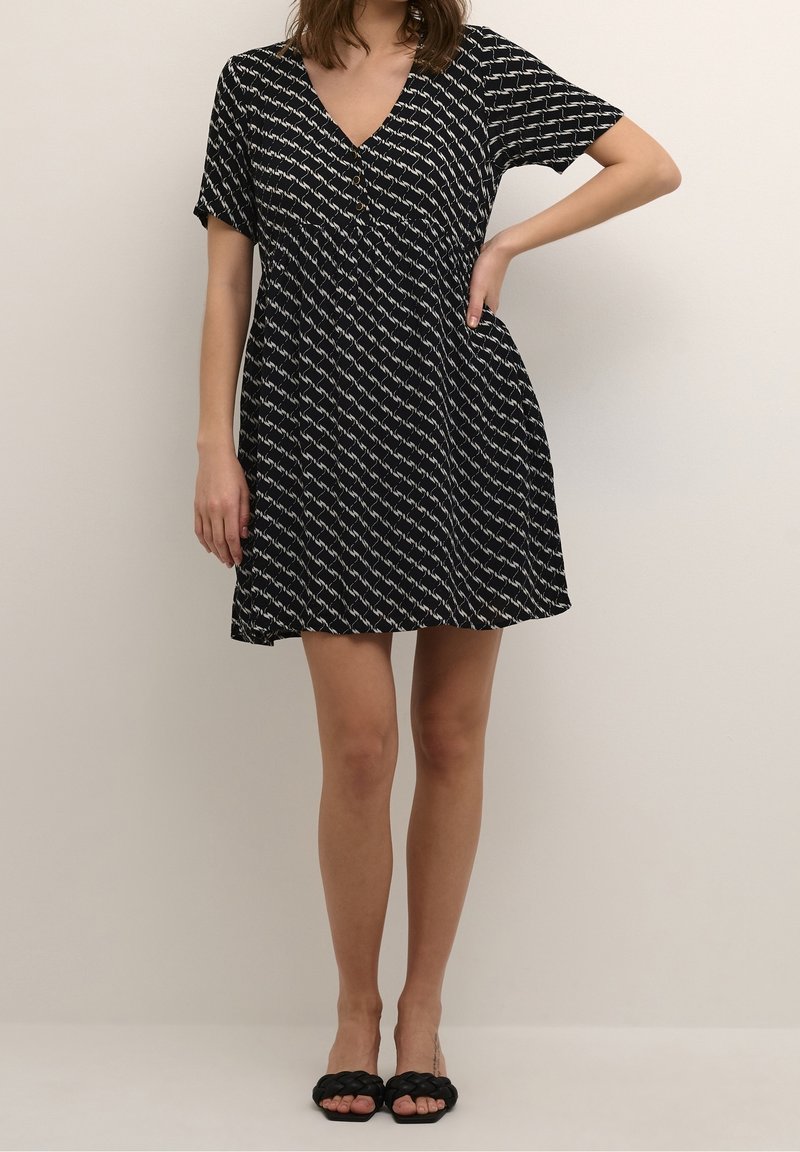 Schwarzes kurzärmeliges Kleid mit V-Ausschnitt und gemusterter Verzierung. Es hat einen ausgestellten Rock und Knöpfe am Ausschnitt. Weiche Stoffstruktur.