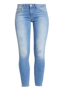 Jeans ajustados de color azul claro con ligeros desgastes, cierre frontal con botón y cremallera, y cremalleras en los tobillos.