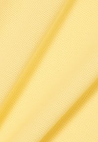 Tessuto tessile di colore giallo chiaro con superficie testurizzata a rete. Morbido e leggero, adatto per abbigliamento o accessori.