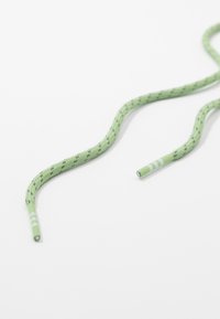 Zielony sznurowadło w wzory o plecionej fakturze, z jednokolorowymi końcówkami i naprzemiennymi paskami w pobliżu końców.