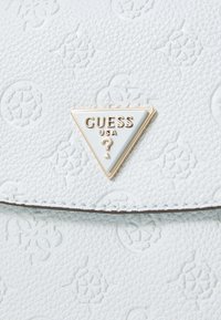 Light blue textured synthetic handbag with embossed patterns, featuring a triangular brand logo in gold and white on the front.