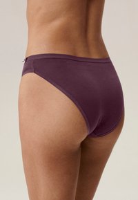 Fioletowe bawełniane figi o gładkiej teksturze, niskim kroju i minimalnych detalach szwów. Tył ma pełne pokrycie i jest ciasno dopasowany.