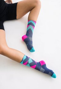 Kniestrümpfe mit einem geometrischen Muster in Marineblau, Pink und Türkis. Glatte Textur mit kontrastierenden Zehen- und Fersendetails.