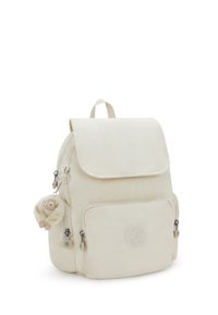 Pequeña mochila beige con un bolsillo frontal, cremalleras laterales, tapa superior y un llavero de mono esponjoso sujetado a la cremallera lateral izquierda.