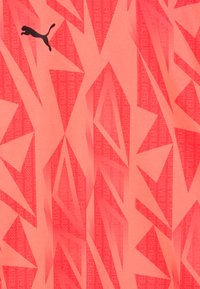 Puma sportkledingstof in helder koraal met een geometrisch patroon van scherpe hoeken en de tekst "FOREVER FASTER" in een lichtere tint gedrukt.