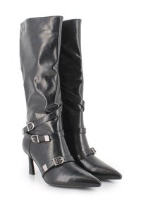 Botas negras de tacón alto con puntera afilada. Confeccionadas en cuero brillante, presentan hebillas y correas plateadas como detalle. Diseño de caña alta.