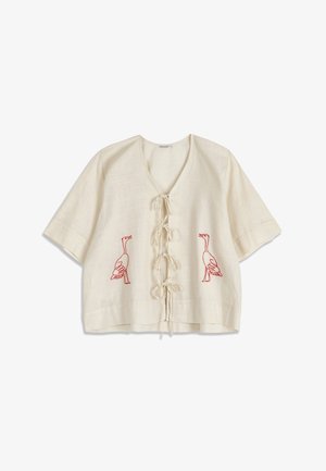Blouse crème à manches courtes avec liens à l'avant et motifs brodés d'oies rouges de chaque côté.