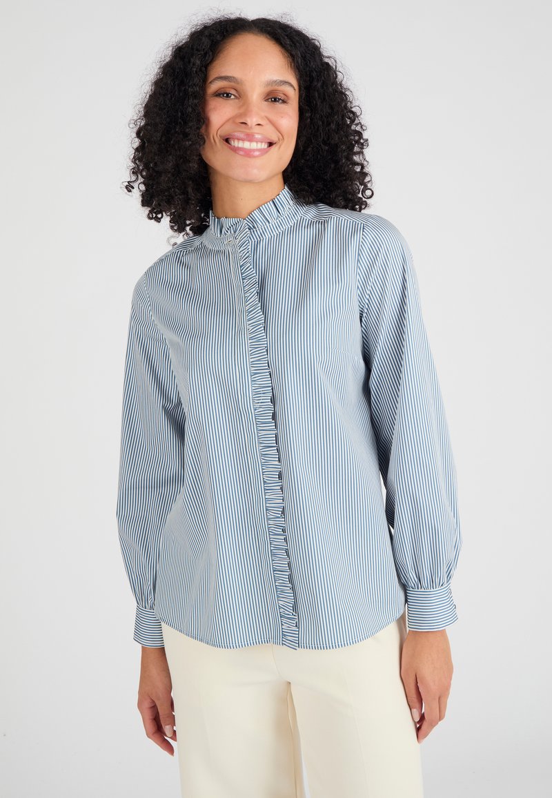 Lichtblauw en wit gestreept overhemd met een gerimpelde stolpplooi, hoge kraag en lange mouwen, gecombineerd met crèmekleurige broek.
