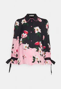 Blusa floreale con un corpo nero e dettagli rosa, maniche lunghe con polsini elastici e bottoni rosa, realizzata in tessuto liscio.