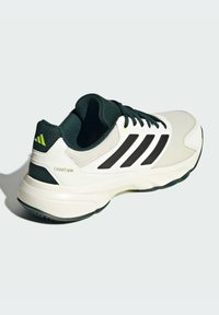 Chaussure de sport blanche et vert foncé avec trois rayures noires, tige en maille, semelle en caoutchouc texturé et détail de marque 'COURTJAM' sur le côté.