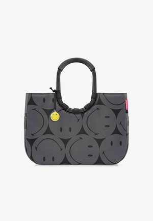 Grijze draagtas van duurzaam materiaal, met een patroon van zwarte lachende gezichten, een ronde zwarte handgreep en een gele glimlachende charme.