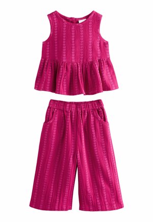 Bez rękawów fuksjowy top z teksturą w serduszka i falbankowanym dołem, połączony z pasującymi, szerokimi spodniami z elastycznym pasem i kieszeniami.