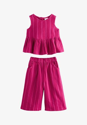 Ujjatlan fukszia felső, szívmintás textúrával és fodros szegéllyel, hozzáillő bőszárú nadrággal, rugalmas derékrésszel és zsebekkel.