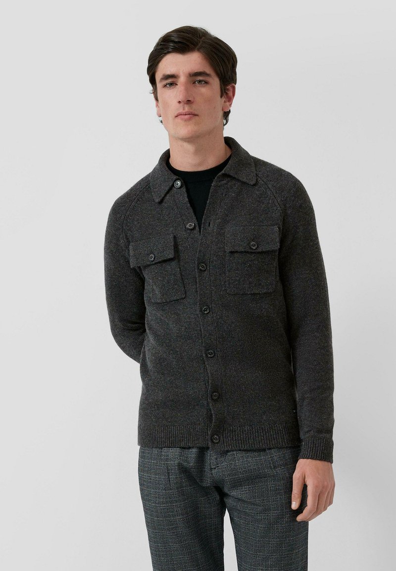 Szary kardigan z teksturowanego materiału, z przodem zapinanym na guziki, dwoma naszywanymi kieszeniami oraz kołnierzykiem.