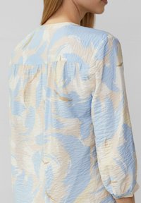 Lichte blouse met een gekreukt textuur en een wervelend patroon in pastelblauw, crème en vleugjes goud, ronde halslijn en driekwart mouwen.