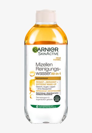 Eau micellaire Garnier SkinActive, bouteille transparente, forme ronde, capuchon crème clair, avec un liquide orange visible, étiquetée comme résistante à l'eau et adaptée aux peaux sensibles.