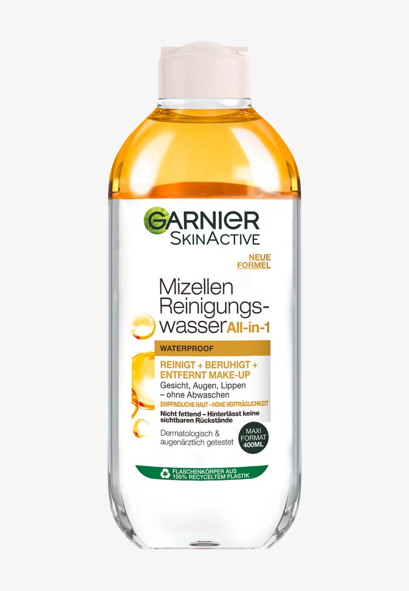 Woda micelarna Garnier SkinActive, przezroczysta butelka, okrągły kształt, jasna kremowa nakrętka, z widoczną pomarańczową cieczą, oznaczona jako wodoodporna i odpowiednia do wrażliwej skóry.