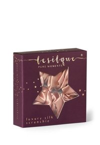 Boîte violette avec une fenêtre en forme d'étoile montrant un chouchou en soie rose de luxe à l'intérieur, marqué "le silque pure moments" sur l'emballage.
