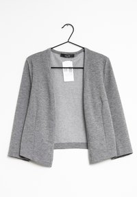 Grå kardigan i mjukt tyg, med öppen framsida, långa ärmar och utan knäppningar. Hänger på en svart plastgalge.