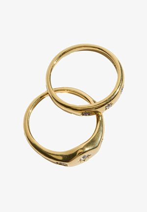 Two gold rings with small embedded stones arranged on a white background, one ring slightly overlapping the other.