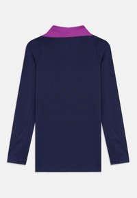 Chemise à manches longues en marine avec un col violet contrastant. Texture lisse, design ajusté et sans motifs ni gravures visibles.