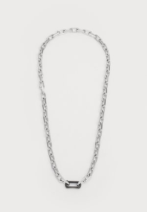 Silver metal chain necklace featuring elongated links and a central black accent link. Smooth texture with polished finish.
