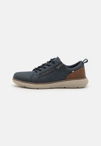 Zapatos casuales para hombre en azul marino con una textura suave, un acento de cuero marrón en el talón, cordones oscuros y una suela de color claro.