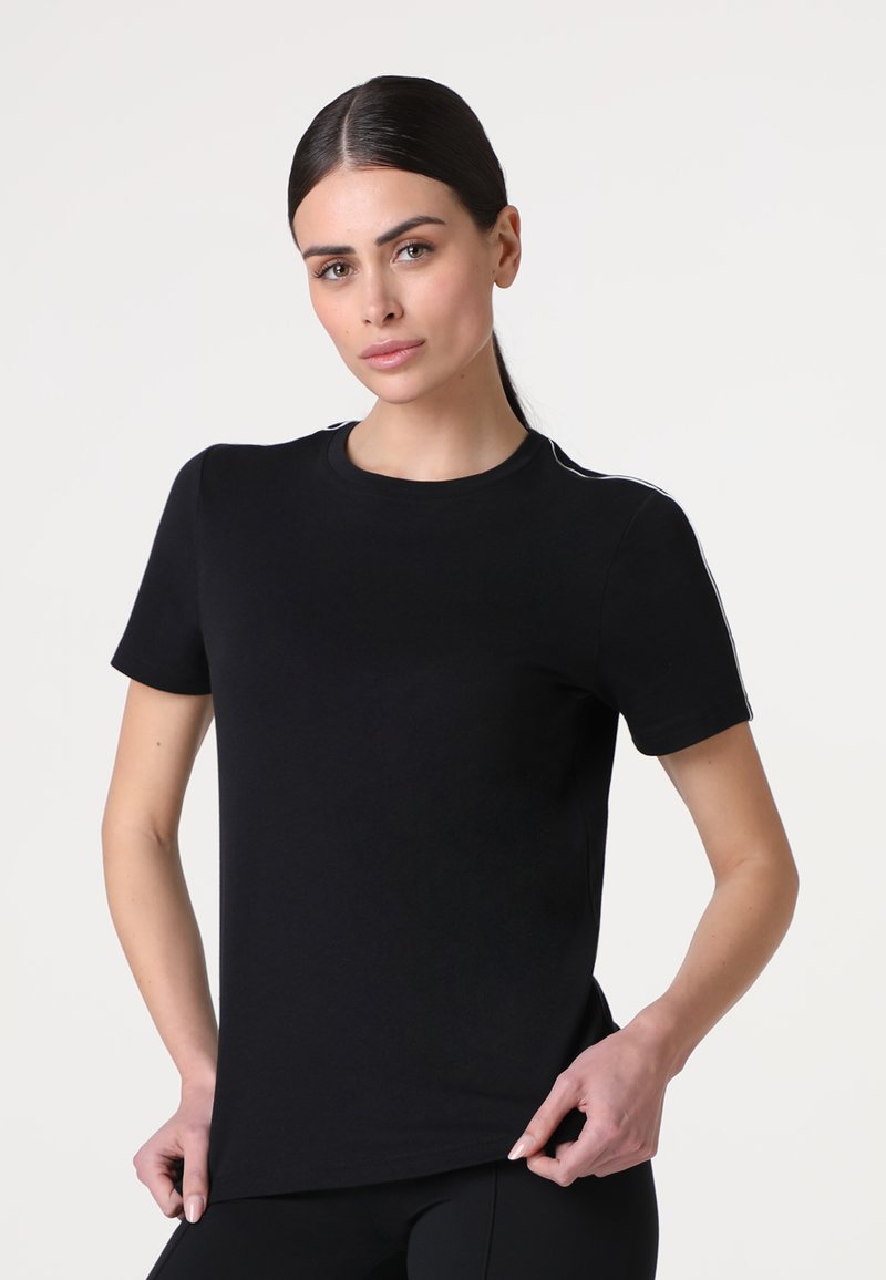 T-shirt nera a maniche corte, scollatura rotonda, realizzata in tessuto morbido. Presenta strisce bianche a contrasto lungo le spalle. Forma aderente.