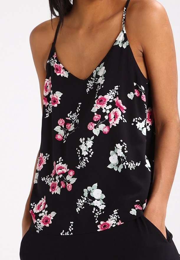 Top en cami floral noir présentant un décolleté en V, des bretelles fines, et un motif de fleurs roses et vertes sur un fond sombre. Tissu léger.