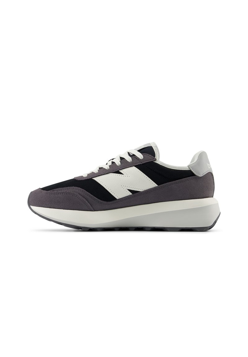Sportliche Schuhe mit einem schwarzen Mesh-Obermaterial, grauen Wildlederakzenten, weißem Logo und einer dicken weißen Zwischensohle. Strukturiertes Gummiprofil für besseren Halt.