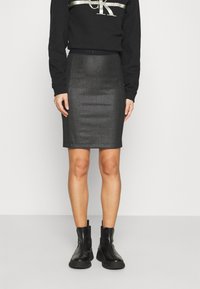 Black sweatshirt with metallic logo detail, paired with a fitted, shimmery black pencil skirt and chunky black ankle boots.