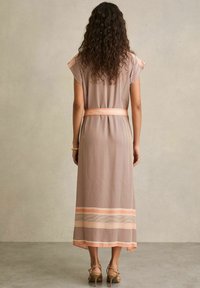 Rochie lungă, cu un model brun, cu mâneci scurte, o curea la talie și un tiv cu dungi roz și albe; textură netedă și material respirabil.