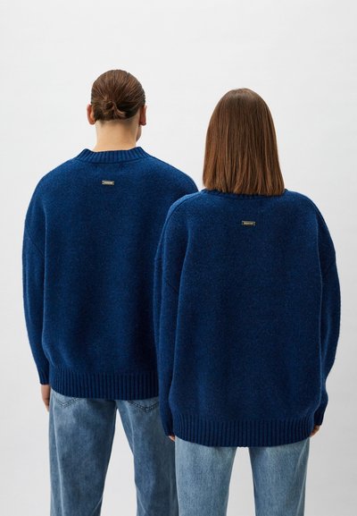 Strickpullover in Tiefblau, mit Rundhalsausschnitt und geripptem Saum. Weicher Griff mit subtiler Schattierung und einem kleinen Markenschild auf der Rückseite.