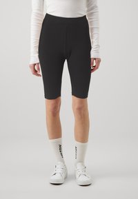 Svarta höga cykelshorts i mjukt material, som når till mitt lår, tillsammans med vita ankelsockor och vita sneakers.