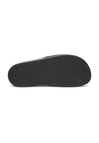 Semelle de chaussure en caoutchouc noir avec un motif de grip texturé et des bords incurvés, présentant une surface lisse et un détail de branding subtil.