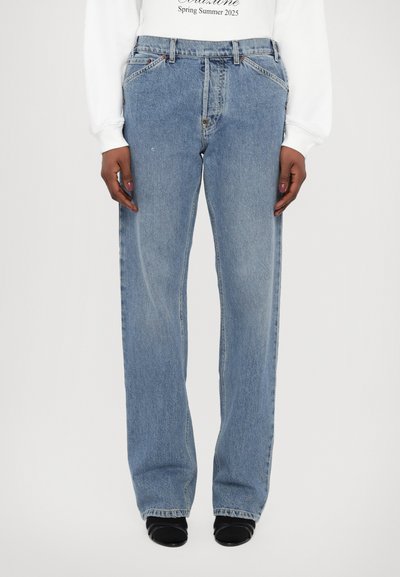 Blå denimjeans med lige ben-design, let slidte tekstur, høj talje og klassisk fem-lomme stil, parret med sorte hæle.