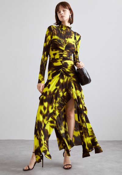 Rochie cu mânecă lungă, în nuanțe de galben și marron cu un model tie-dye, având pliere la față și o fanta înaltă, asortată cu accesorii negre.