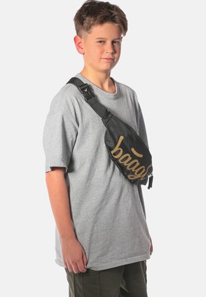 Borsa a tracolla nera con testo dorato, realizzata in materiale resistente, indossata sopra una maglietta grigia, dotata di tracolla regolabile e chiusura con cerniera.