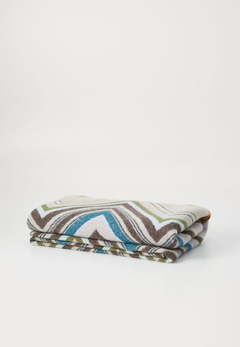 Multicolored blanket with zigzag patterns in shades of brown, green, blue, and cream, folded neatly. Soft texture and lightweight design.
