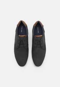 Baskets en mesh noir avec des accents en cuir marron. Dotées de lacets plats, d'une semelle intérieure rembourrée et d'une semelle en caoutchouc blanche.