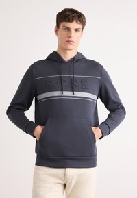 Hanorac cu glugă de culoare bleumarin închis, cu un buzunar frontal tip kangaroo, având un logo "BOSS"  în relief și dungi orizontale gri contrastante.