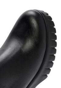Bottine en cuir noir avec un bout rond, surface texturée et une semelle épaisse et rainurée pour une meilleure adhérence. Design minimaliste avec des lignes épurées.