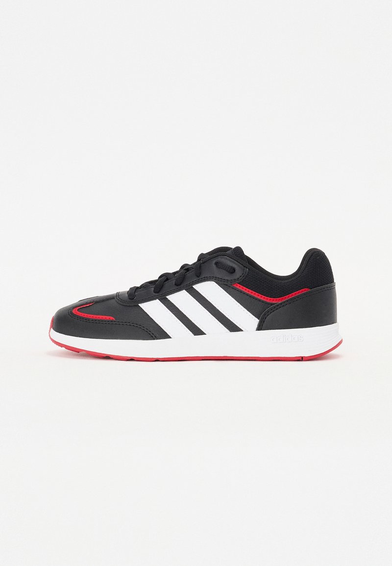 Scarpa sportiva nera con strisce bianche, accenti rossi, suola in gomma e una parte superiore liscia. Presenta un design con lacci e una punta rotonda.