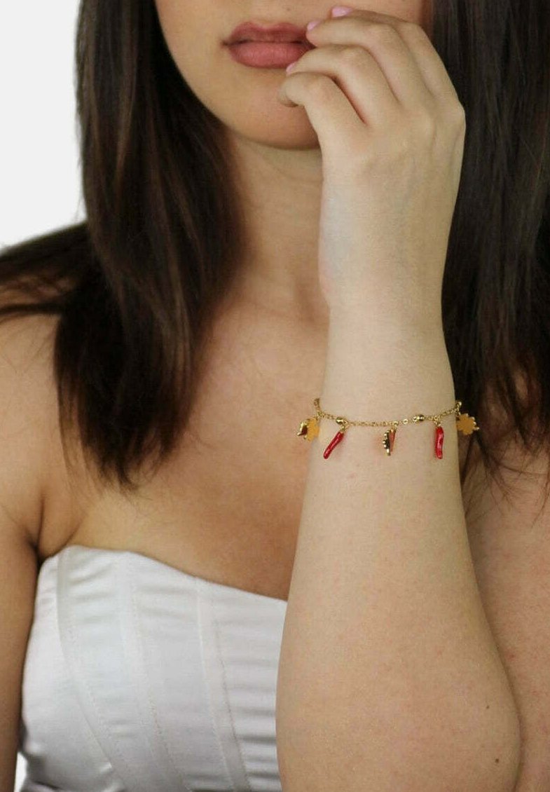 Bracciale in oro con charm a forma di peperoncino rosso. Texture liscia, design delicato e misurabilità regolabile. Gli accenti includono piccoli elementi dorati.
