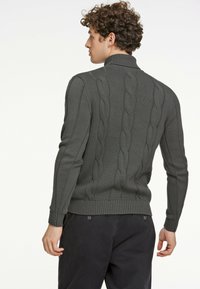 Maglione a coste verde scuro con colletto alto, caratterizzato da dettagli in lavorazione a treccia lungo la schiena e polsini aderenti.
