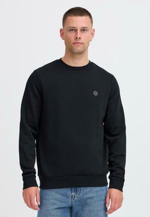 Svart sweatshirt med rund halsringning och långa ärmar, med en liten logotyp på vänster bröst. Mjukt tyg och ribbade ärmslut och nederkant.